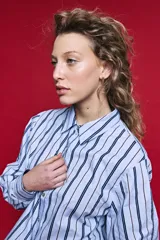 Camisa de algodón celeste con rayas verticales azul marino y marrón, cuello camisero clásico y cierre frontal de botones nacarados.