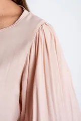 Blusa color rosa pálido, de manga larga abullonada con puño elástico y escote redondo.