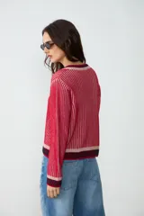 Cardigan de punto con escote en V y cierre frontal de botones. Diseño rayado en tonos rojo, rosado y azul marino, de manga larga.