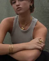 Collar de cadena de eslabones alargados con cierre frontal tipo T y dije circular de textura rústica e irregular.