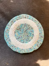 Boina tejida en crochet de lana merino con diseño circular en tonos celeste, blanco, gris y tostado.