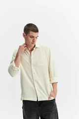 Camisa rústica de manga larga color gris oscuro, con cuello clásico, cierre frontal con botones y un bolsillo aplicado en el pecho.
