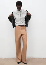 Jersey de punto fino color gris claro, de corte recto y manga larga, con cuello alto y detalle de lazada en el cuello.