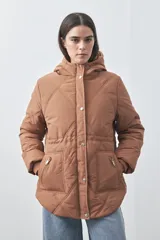Campera puffer negra con diseño acolchado, capucha integrada y cierre frontal con botones a presión. Presenta puños elásticos y costuras decorativas en el frente.