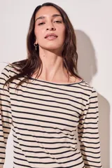 Remera de algodón color crema con rayas horizontales negras, cuello bote y mangas largas.