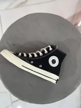 Zapatillas de lona negras de caña alta con cordones blancos y suela de goma color crema. Logo de Peach engomado en la base y en la cara interna.