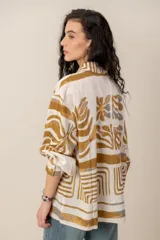 Camisa de manga larga de corte holgado, color blanco con estampado abstracto y floral en tonos ocre y azul.