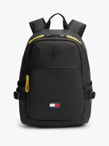 Mochila negra de poliuretano con compartimento principal y cierre de doble cremallera con tiradores amarillos a contraste. Cuenta con bolsillo frontal con cremallera, asa superior, correas ajustables y acolchadas, y parche engomado de Tommy Jeans en la parte delantera.