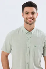 Camisa de manga corta confeccionada en mezcla de lino y algodón, color beige, con cuello camisero abotonado, bolsillo frontal en el pecho y cierre de botones.