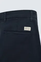 Pantalón chino de corte ajustado, color beige, con bolsillos laterales y bolsillos traseros de vivo. Cuenta con cierre frontal de cremallera y botón.