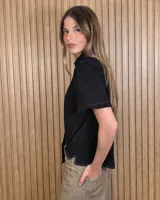 Camisa de manga corta color beige, con cuello alto con volados, botonadura frontal y mangas abullonadas con terminación fruncida.