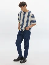 Pantalón de jean azul oscuro, corte slim, tiro medio y confeccionado en denim 100% algodón crudo.