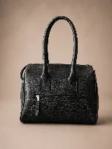 Cartera de mano estructurada de cuero vacuno rojo, con doble asa superior y detalles de charol en la parte superior. Cuenta con cierres metálicos y apliques decorativos laterales con hebillas.