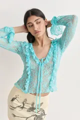 Top blanco de encaje con escote en V, volados y mangas largas con lazos.