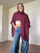Ruana tejida de algodón con hilo lurex en punto jersey, color azul, con diseño amplio y detalle de etiqueta de cuerina en la parte posterior.