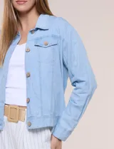 Campera de denim liviano azul, de corte clásico y silueta recta, con cuello camisero, cierre frontal con botones rústicos y bolsillos con solapa en el pecho.