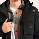 Campera de microfibra negra con relleno de guata y forro interior polar. Presenta cierre frontal completo, capucha ajustable con cordones, dos bolsillos frontales con solapa y corte estilo parka hasta la cadera. Cuenta con recubrimiento resistente al agua y al viento.