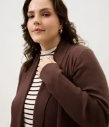 Cardigan de punto color marrón, con diseño alargado y puntas asimétricas. Presenta mangas largas, cuello tipo chal y detalles de textura canelada en los laterales.