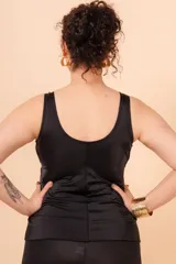 Camiseta tankini negra con escote en V, vivos blancos en contraste y aplique de aro metálico en el cinto. Incluye bolsillo interno en el busto para colocar copa removible o prótesis externa.