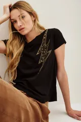 Remera negra de manga corta con cuello redondo y un aplique grande en forma de rayo. El rayo está decorado con lentejuelas doradas y negras.