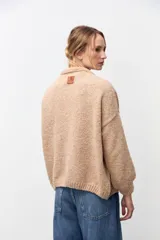 Cardigan de punto abierto en color beige, con diseño de corte holgado, mangas largas con puños acanalados y textura suave.