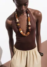 Collar de diseño ajustable con cuentas de resina, acrílico y plástico en tonos tierra, marrones y dorados, con cierre de cordón negro.