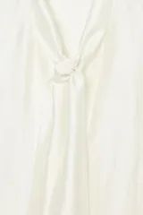 Camisa de corte holgado confeccionada en tejido satinado con mezcla de lyocell. Presenta cuello redondo con escote en pico y lazada frontal integrada. Cuenta con mangas largas abullonadas terminadas en puños anchos y bajo recto.