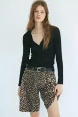 Bermuda de cinco bolsillos en denim de algodón rígido, con tiro alto, cierre y botón, y estampado animal print de leopardo.