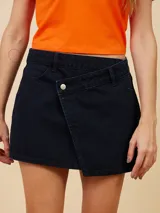 Minifalda de jean azul oscuro con diseño cruzado en el frente y un botón metálico.