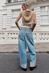Jeans baggy de tiro medio con pernera holgada, diseño de cinco bolsillos y bajo acabado en vuelta. Cuenta con cintura elástica en la espalda y cierre frontal con cremallera y botón.