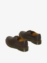 Zapato de tres ojales Dr. Martens modelo 1461, confeccionado en cuero Crazy Horse de color marrón con acabado encerado. Presenta costuras amarillas visibles en el borde de la suela y suela de goma con cámara de aire.