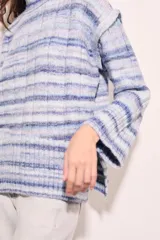 Polera celeste con rayas horizontales en tonos de azul y blanco, de cuello alto y corte oversize.