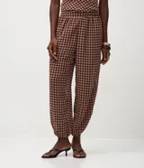 Pantalón modelo aladino de corte holgado y fluido, confeccionado en chiffon con estampado de cuadros. Presenta cintura elástica y puños ajustados en el dobladillo, ofreciendo una silueta tipo globo.