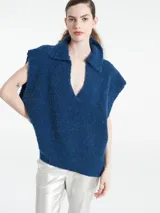 Poncho de punto color azul, con cuello polo y escote en V profundo, sin mangas y diseño holgado.