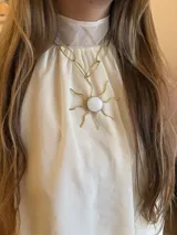 Collar con cadena de eslabones grandes en bronce y dije colgante con forma de sol. El centro del sol es una pieza redonda de nácar engarzada.