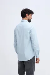 Camisa de manga larga fit semi slim color celeste, con cierre frontal de botones y cuello camisero clásico.