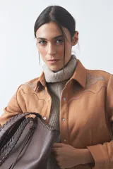 Sobrecamisa de gamuza color marrón con bordados decorativos estilo western en la zona de los hombros y cierre frontal con botones metálicos.