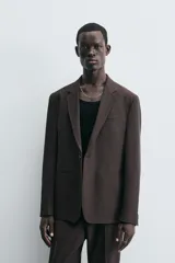 Blazer de corte regular fit confeccionado en tejido con lana. Presenta cuello con solapas de muesca, cierre frontal de un botón, bolsillos de vivo en el pecho y en la cadera, y aberturas en la espalda.