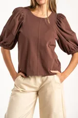 Remera de algodón negro con mangas cortas abullonadas, cuello redondo y costura central frontal.