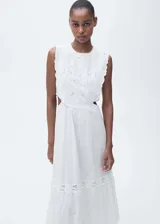 Vestido largo de algodón blanco con diseño sin mangas, cuello redondo y aberturas laterales en la cintura. Presenta un delicado bordado floral calado en la parte superior y en el ruedo, con una falda de corte evasé.