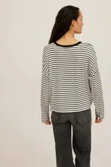 Remera manga larga de corte holgado y hombros caídos con diseño de rayas horizontales en blanco y negro, con cuello redondo negro en contraste.