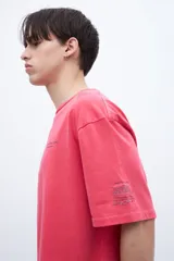 Remera gris con cuello redondo, mangas cortas y calce oversize. Presenta un pequeño estampado en el pecho y un bordado en la manga. Confeccionada en algodón lavado con textura extra suave y tela jersey pesado.