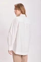 Camisa blanca de mangas largas con hombreras y cuello clásico.