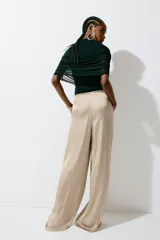 Pantalón fluido de satén color beige, de corte holgado y piernas amplias, con cintura elástica fruncida y cordón ajustable.