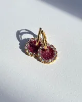 Aros de acero quirúrgico con dije circular de resina rosa y borde de strass dorados.