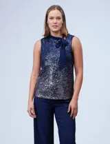 Blusa azul de microtul bordado con lentejuelas, marca Cable & Gauge. Cuello alto en gasa, escote asimétrico y lazo de ajuste.