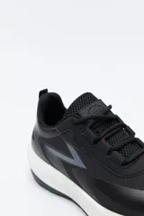 Zapatilla deportiva de diseño dinámico, confeccionada en material técnico con paneles en contraste. Presenta un diseño lateral con forma de rayo en tono marrón, ajuste con cordones y suela robusta con relieve.