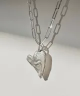 Collar plateado con cadena de eslabones rectangulares y dije irregular con forma de corazón.