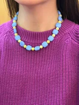 Collar corto de cuentas, compuesto por cuentas cuadradas celestes intercaladas con cuentas esféricas amarillas pequeñas.