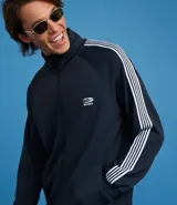 Campera deportiva de cuello alto con cierre frontal completo, mangas largas con rayas laterales blancas contrastantes y bolsillos laterales. Presenta un bordado pequeño en el pecho.